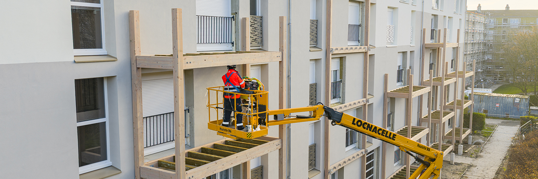 Un compagnon de Sotram sur une nacelle procède à la pose de balcons en façades d'un immeuble à Reims